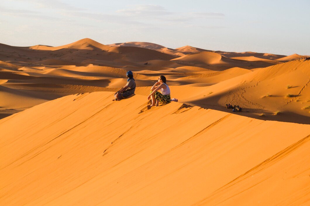 extreme-long-shot-two-people-sitting-top-dune_23-2148194013